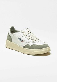 Sneaker bianca con inserti in camoscio grigio, punta traforata, linguetta testurizzata e suola in gomma beige. Presenta lacci e dettagli del logo del marchio.