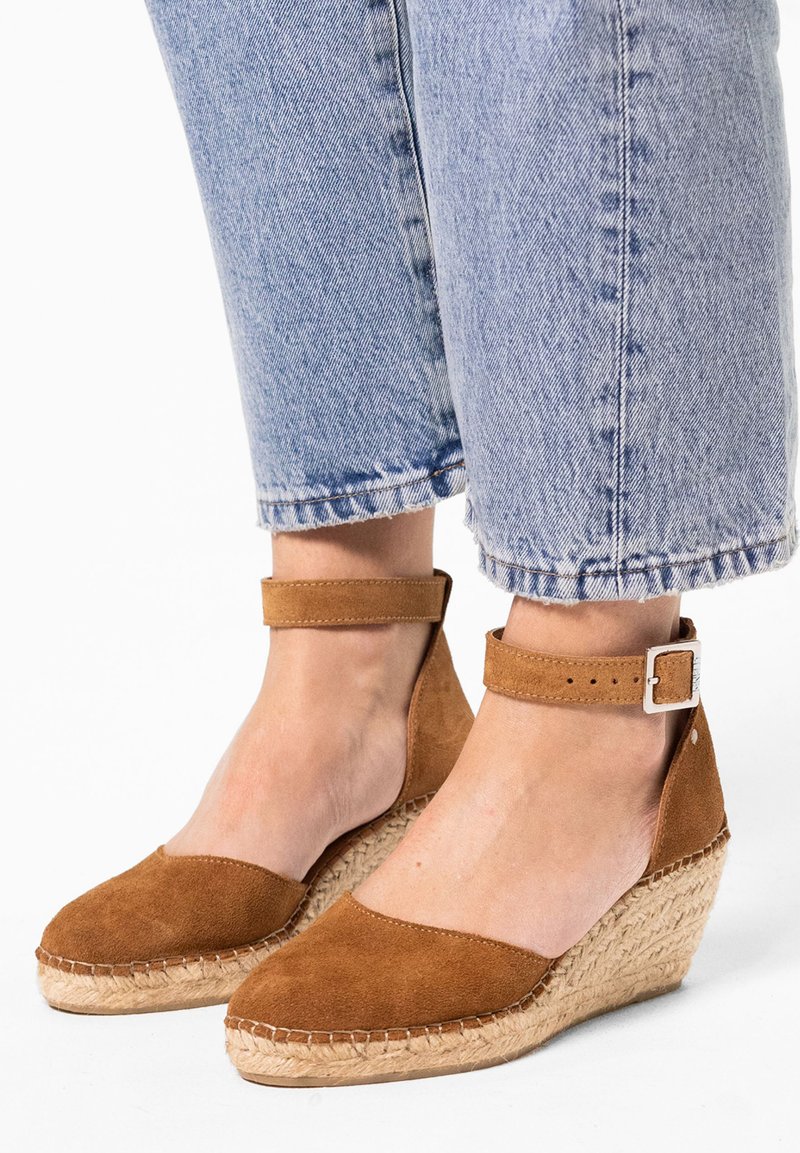 Braune Wildleder-Wedge-Sandaletten mit Knöchelriemen, gewebter Jutesohle und abgerundeter Zehe, kombiniert mit hellen, gewaschenen, kurz geschnittenen Jeans.
