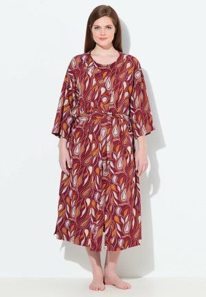 Robe longue à motifs rouges et blancs avec des manches larges, taille cintrée et une silhouette fluide. Le tissu a une texture lisse, idéale pour le confort.
