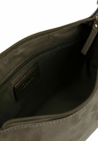 Innenseite einer olivgrünen Stofftasche mit einer glatten Textur, ausgestattet mit einer Reißverschlusstasche und einem Lederetikett. Keine sichtbaren äußeren Details.