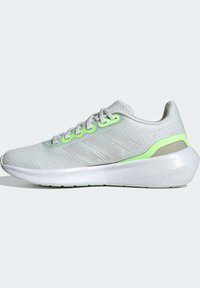 Chaussure de course gris clair avec semelle blanche, œillets vert néon et accents au talon, et un design subtil à trois bandes sur le côté.