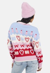 Maglione lavorato a maglia in blu chiaro, rosa e rosso con motivi zigzag, cuori e fiocchi. Il testo recita "HO" e "HI". Include un cappello rosa testurizzato.
