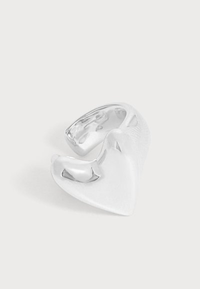 Un protège-dents en silicone transparent, doté d’une partie supérieure transparente, sur un fond uni et clair.
