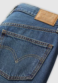 Donkerblauwe spijkerbroek van denim met een gestructureerde uitstraling, voorzien van oranje stiksels, een leren merklabel en een kenmerkend ontwerp van de achterzak.