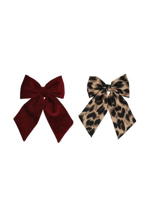 Due fiocchi decorativi in tessuto affiancati, uno rosso scuro con glitter e uno beige con macchie nere leopardate.