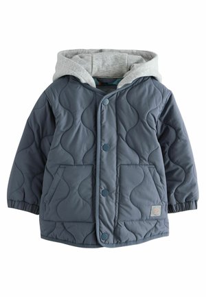Veste rembourrée bleu marine avec texture matelassée, capuche grise, boutons pression et poches avant. Présente un patch logo sur le bas.