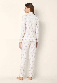 Set de pijamale cu mânecă lungă, având un fundal roz deschis cu diverse modele de animale. Fabricat dintr-un material moale, are o croială lejeră și mansete.