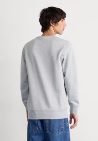 Grijze katoenen sweatshirt met ronde hals, ribgebreide mouwen en onderkant. Eenvoudig ontwerp, met een zachte textuur en een relaxte pasvorm. Zichtbare naden bij de schouders.