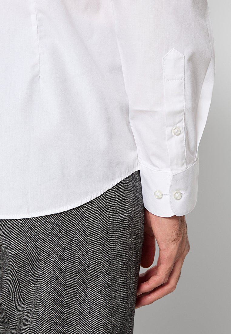 Witte lange mouwen shirt met een gladde textuur, spitse manchetten met twee witte knopen, gecombineerd met gestructureerde houndstooth patronen broek.