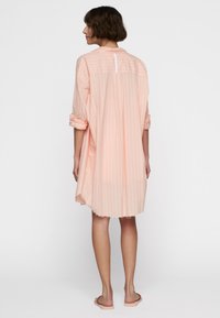 Vestito leggero color pesco con sottili righe verticali, colletto alla cinese e maniche arrotolate, con apertura centrale sul retro con bottoni.