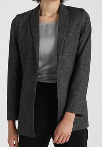 Grå kavaj i strukturerad tyg, med notched lapel, öppen front och långa ärmar. Bärs över en ljusgrå topp.