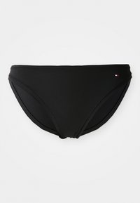Svart lavprofil bikini-truse med en liten rektangulær rød, hvit og blå logo på høyre hofte, vist på en ensfarget hvit bakgrunn.