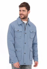 Chaqueta impermeable azul claro con cuello amplio, cuatro bolsillos delanteros y cierres de botones. Fabricada con tela suave y corte estructurado.
