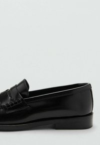 Czarne skórzane mokasyny z zaokrąglonym noskiem, ozdobione teksturowanymi akcentami na przodzie i niskim, prostokątnym obcasem. Gładka powierzchnia.