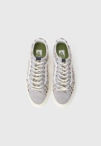 Zapatillas con una parte superior de tejido texturizado en gris y crema, cordones blancos, plantillas de color verde oliva y una suela de goma duradera en blanco roto.