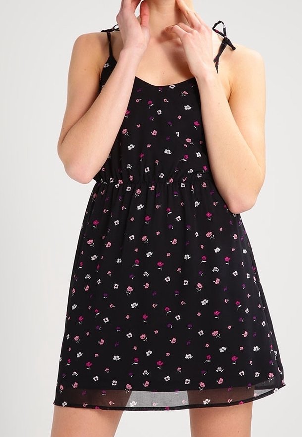 Robe noire à fleurs avec de petites fleurs roses et blanches. Tissu léger, corsage ajusté et bretelles réglables. Détail de taille froncée.