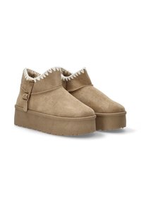 Botas de tobillo de ante beige con suela de plataforma, que cuentan con un forro de piel sintética y costuras decorativas a lo largo del cuello. Detalle de hebilla en el costado.
