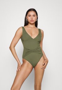Maiô verde-oliva com decote em V profundo, alças largas e detalhes drapeados nas laterais. Tecido suave e elástico com um corte justo.