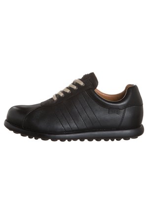 Zapatilla casual de cuero negro con cordones gris claro, cuello acolchado y suela de goma texturizada, vista desde un lado sobre un fondo blanco.