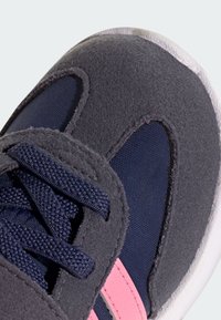 Sive i mornarski tenisice s ružičastim naglascima, s teksturiranim gornjim dijelom, glatkim dijelom za vezanje i bijelim gumenim potplatom.