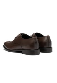 Pantofi de dama din piele maro cu un finisaj neted, vârful rotund și design cu șireturi. Talpă robustă cu un ușor toc și detalii de cusături accentuate.