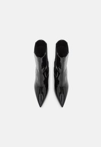 Kotníkové boty z černé lakované kůže s špičatou špičkou a elastickými bočními panely. Hladký povrch a elegantní design pro štíhlý vzhled.