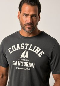 Camiseta de algodón gris oscuro con texto blanco que dice "CLUB DE NAVEGACIÓN COASTLINE SANTORINI Grecia 1880" y un gráfico de velero en el centro.