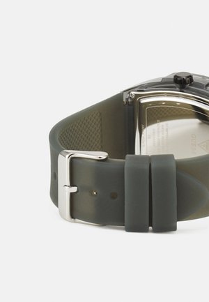 Dunkelgrünes Silikon-Uhrenarmband mit einer silbernen Metallschließe. Verfügt über ein strukturiertes Muster auf der Unterseite und ein Gehäuse aus rostfreiem Stahl.