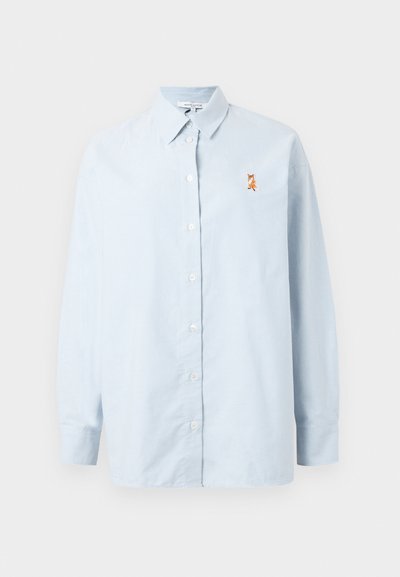 Šviesiai mėlyna ilgomis rankovėmis palaidinė iš minkštos medžiagos, su mygtukais priekyje ir brodiniu lapių dizainu kairėje krūtinės pusėje.