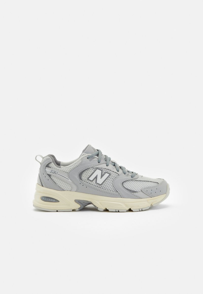Baskets New Balance en mailles grises avec une semelle crème, présentant un design texturé et un logo 'N' bien visible sur le côté.