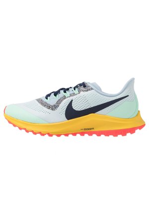Jasnoniebieski but do biegania Nike z czarnym znakiem, żółtą środkową podeszwą, czerwoną zewnętrzną podeszwą i wielokolorowymi kropkami w pobliżu sznurówek.