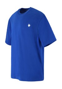 Blauwe katoenen t-shirt met een ronde hals en korte mouwen. Heeft een klein wit bladerenembleem op de linkerborst. Glad van structuur.