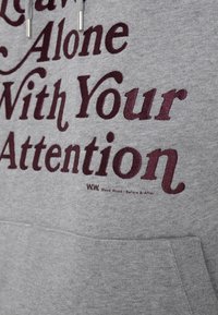 Grå sweatshirt med vinröd text som lyder "Leave Alone With Your Attention." Den har en framficka och huva med dragsko.