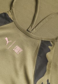 Top deportivo en verde oliva con una tela texturizada, que presenta detalles en negro con camuflaje y el logotipo de Puma junto con "FIRST MILE" en la parte frontal.