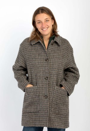 Giacca a quadri marrone, crema e grigio. Presenta un colletto, bottoni frontali e ampie tasche laterali. Realizzata in tessuto testurizzato.