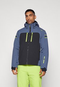 Chaqueta de hombre que presenta la parte superior en azul y la inferior en negro, con detalles en verde, bolsillos con cremallera y capucha para brindar calidez y estilo.