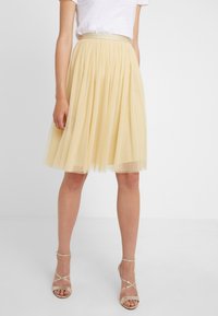 Gonna in tulle di un giallo pallido con un design plissettato. Presenta una vita aderente e una texture leggera, raggiungendo la lunghezza a metà polpaccio.