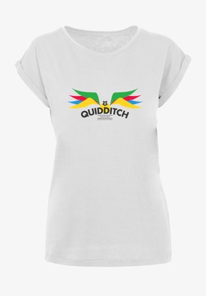 Balta T-kreklā ar sarullētām piedurknēm, uz kura attēlots krāsains Kvidita grafiks ar zaļām, sarkanām, dzeltenām un zilām spārnu stilizējumiem, kā arī melns teksts.