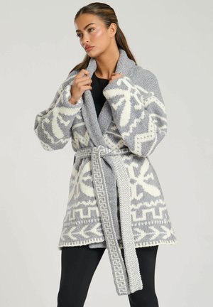 Cardigan tricoté gris et blanc avec un motif géométrique, large col et ceinture. Présente des manches longues et un design décontracté.