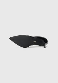 Black pointed-toe stiletto heel shoe shown from the sole, featuring a sleek design and a small metallic logo near the arch.