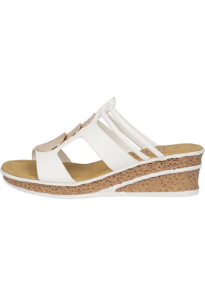 Sandales blanches à talon compensé avec une semelle texturée imitation liège, bout ouvert et accents métalliques décoratifs. Les brides présentent un design entrecroisé pour un meilleur maintien.