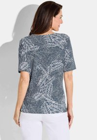 Korte mouwen top in marineblauw met witte bladvormen; zachte, lichte stof; relaxte pasvorm; ronde halslijn; zijsplitten aan de zoom.