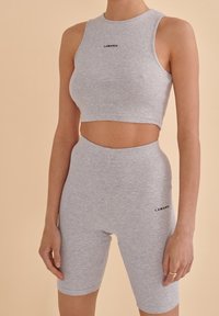 Gray ribbed crop top and high-waisted shorts set, featuring a black logo on the chest and thigh. Soft, stretchy fabric, fitted design.