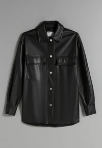 Black faux leather shirt jacket with a collared neckline, two chest pockets, and silver button closures. Features contrasting stitching.