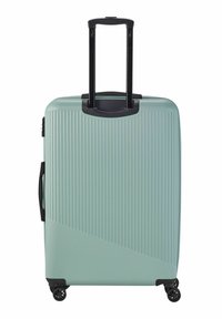 Valise rigide de couleur bleu clair, avec une texture rayée verticale, une poignée noire rétractable et quatre roues noires pour une meilleure mobilité.