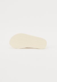 Talpa de pantof din cauciuc de culoare deschisă, cu un model în zig-zag, având margini rotunjite și o textură netedă. Design curat, minimalist.