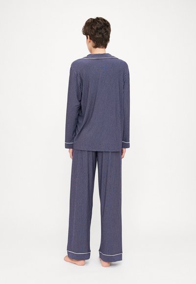 Navy blue striped pajamas featuring a long-sleeve top with a loose fit and matching wide-leg pants, accented with light-colored cuffs.