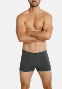 Gray cotton boxer shorts with a snug fit, featuring a black waistband tag. Smooth texture, mid-thigh length, and no visible patterns.