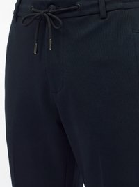 Gros plan sur un pantalon bleu marine avec un cordon noué en nœud et un bouton au-dessus de la ceinture.