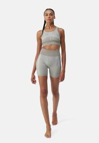 Completo sportivo grigio chiaro composto da reggiseno e pantaloni shorts, realizzato in un tessuto elasticizzato, con un design senza cuciture, cuciture accentuate e una vita alta per un supporto ottimale.
